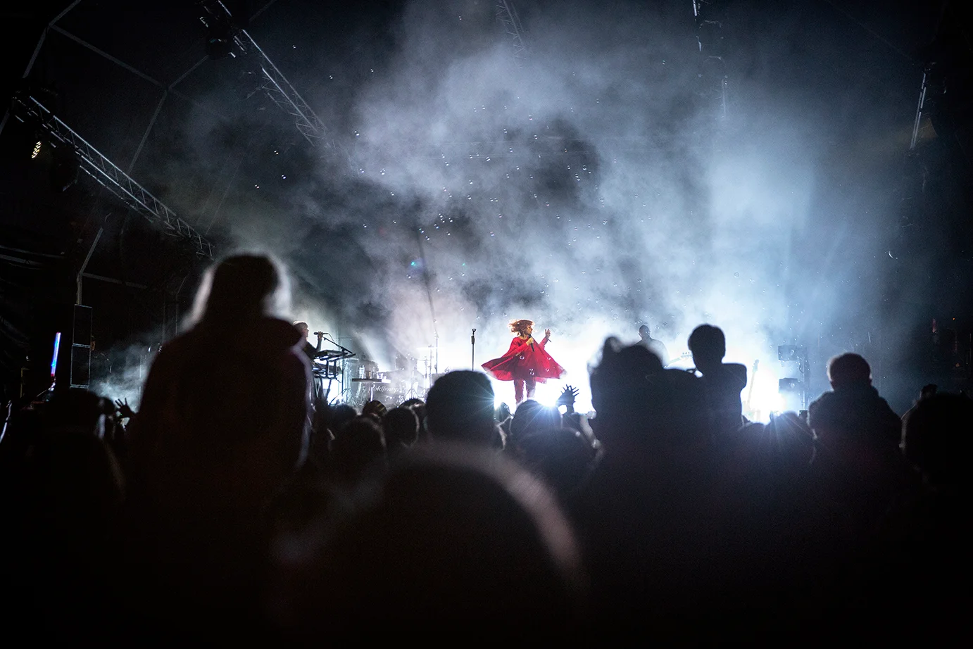 festival - the singer Alison Goldfrapp on stage at night, twirling while wearing a red dress at Deer Shed Festival enveloped by smoke, bubbles and bright lights
